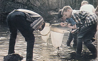 
Visiting children and their intern guide search for aquatic life in a creek.  
